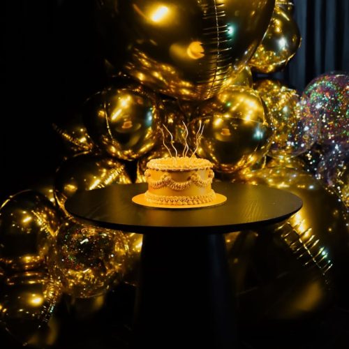 Arco dourado com balões Orbz aplicado à cenografia corporativa para evento empresarial em Itajaí